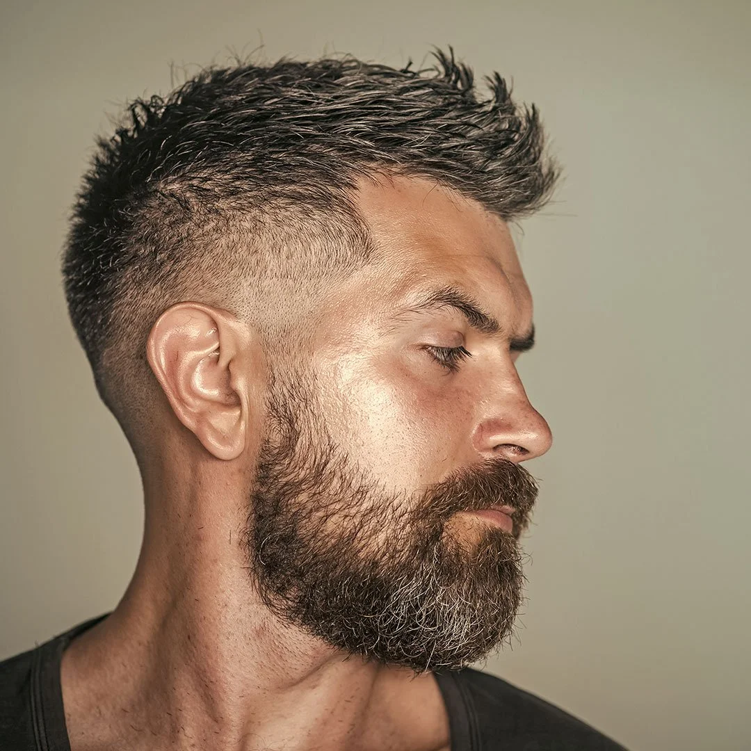Bearded man in a black shirt turning his head to the side.