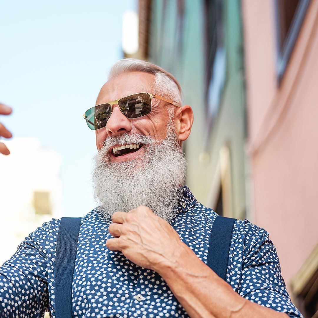 Older bearded man smiling while on the phone.