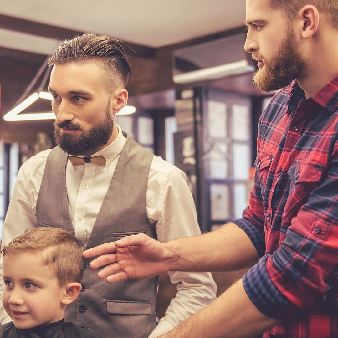 Bearded men and a child inside a barber shop.