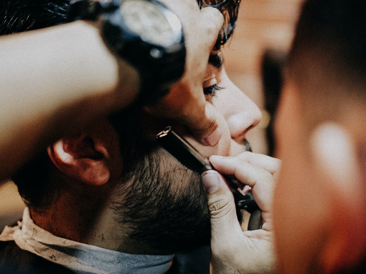 close-up image of barber using razor to line up trimmed beard