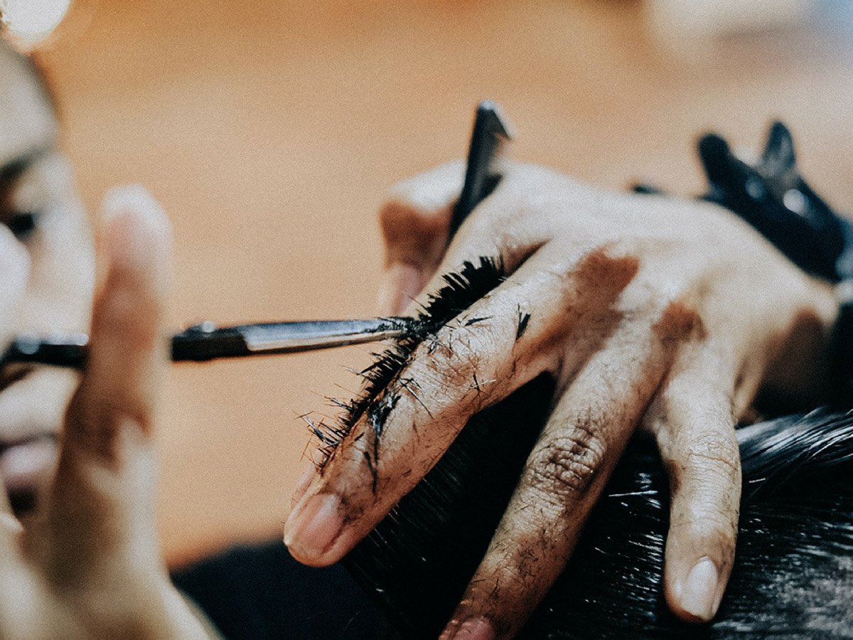 close up of barber’s fingers trimming hair