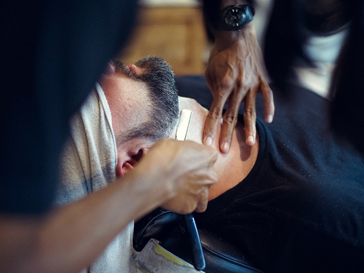 image of man using straight razor to shave neck of client