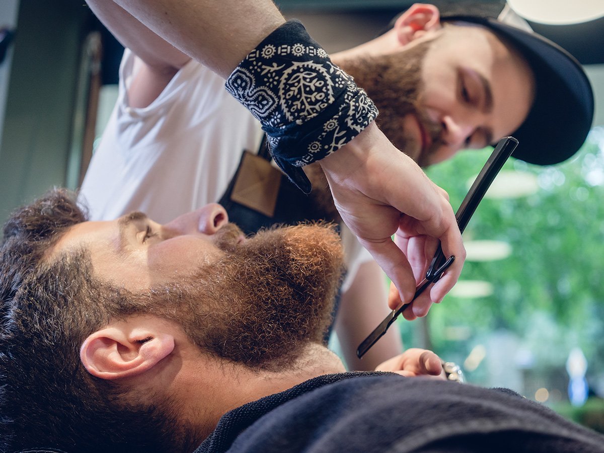 barber trimming man's beard