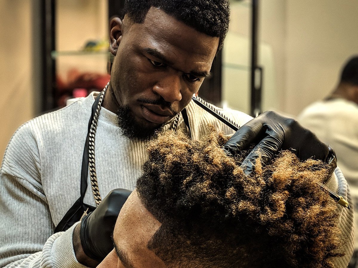 man getting his hair trimmed with electric clippers by a professional barber