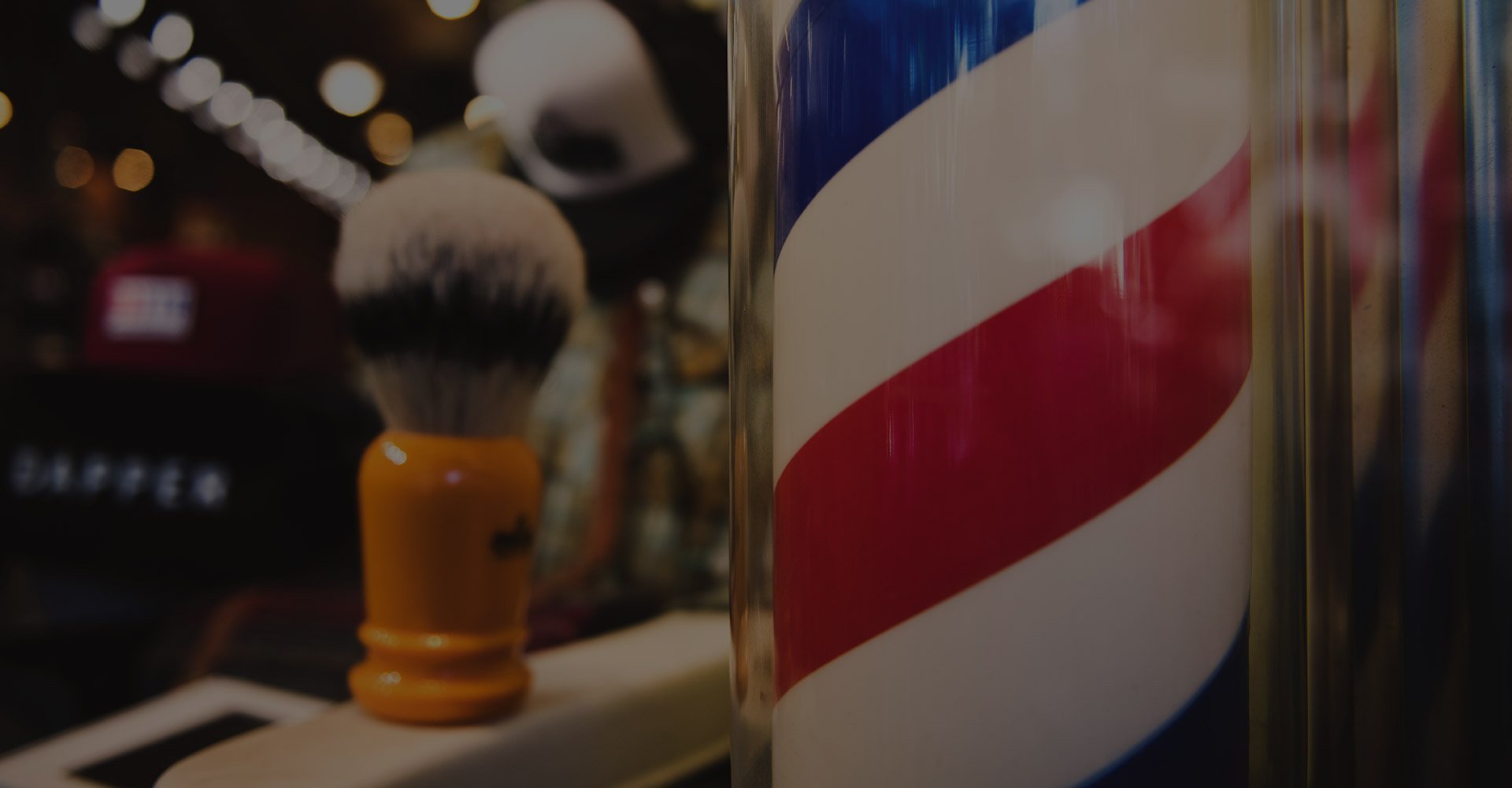 close up of red, white, and blue barber sign and hair tools in the background